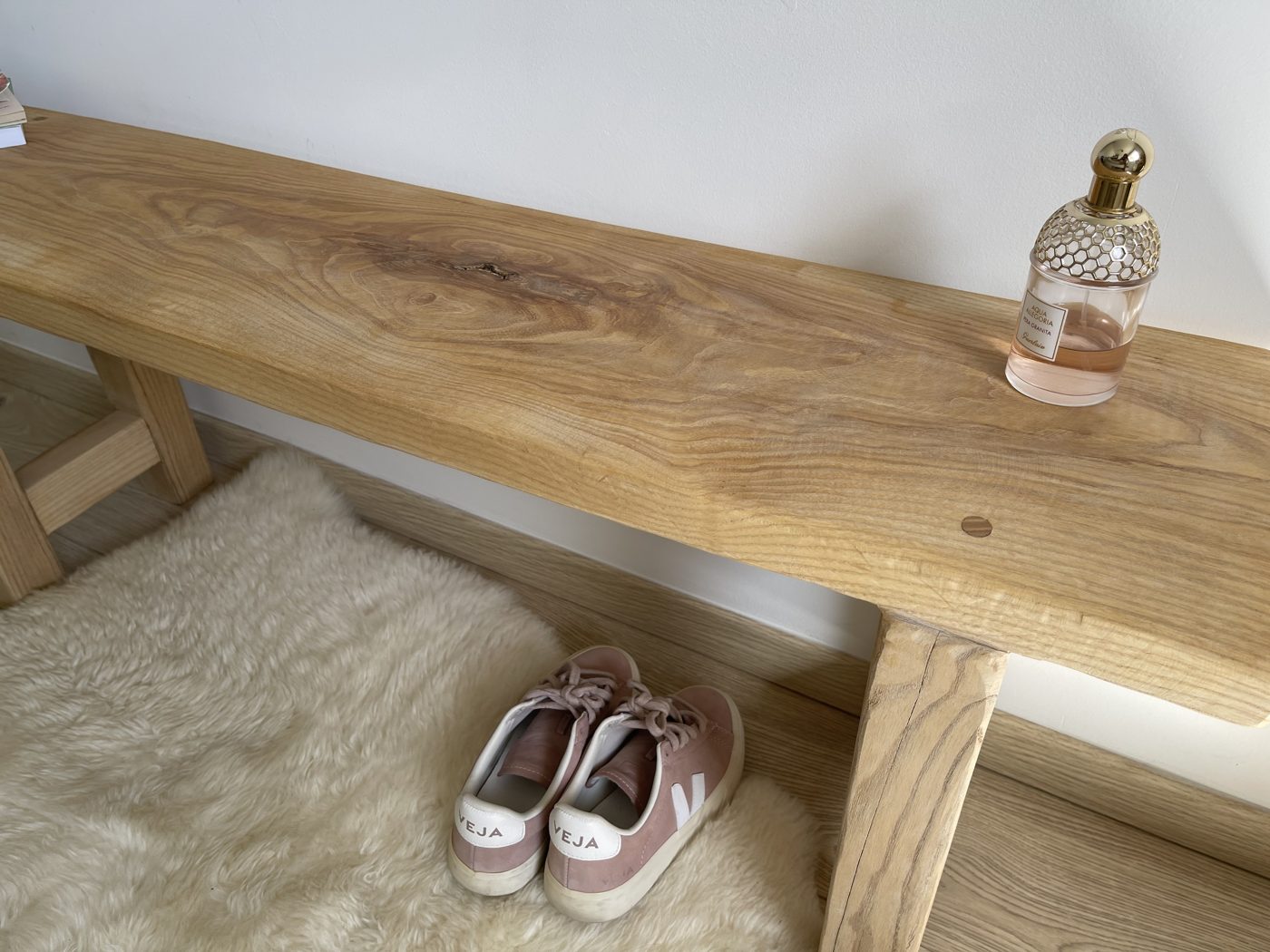 Plateau épais à rive naturelle d'un banc d'entrée, chaussures rangées en dessous