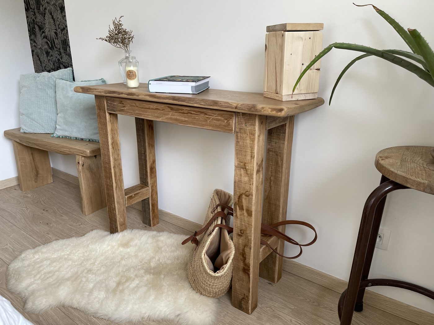 Console haute en bois brut avec objets de décoration et tabouret