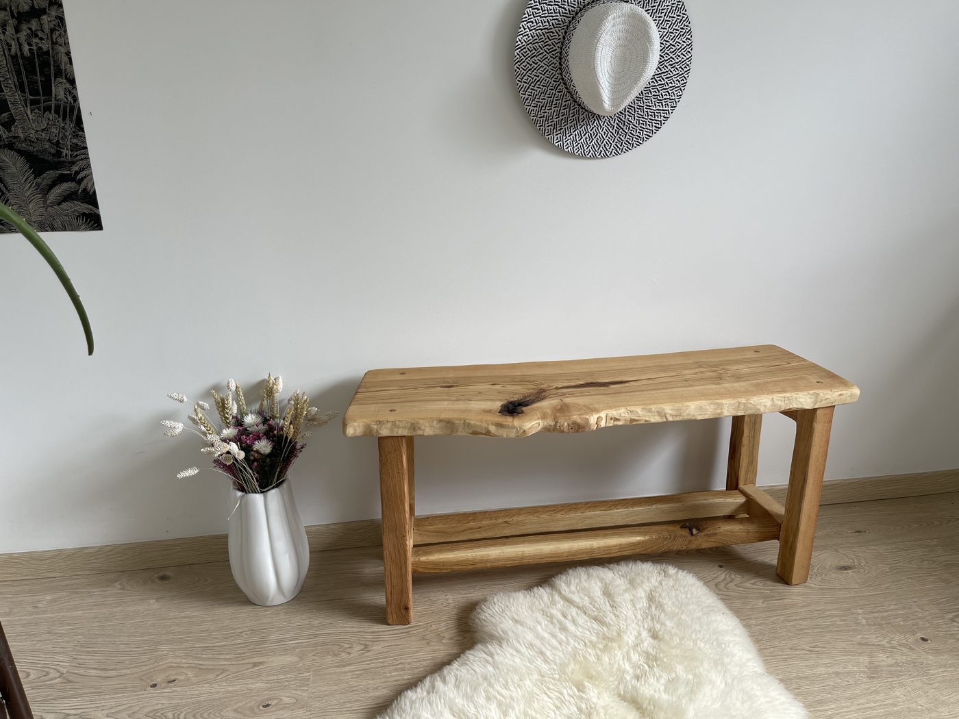 Banc à rive naturelle et étagère basse, vase de fleurs séchées à côté