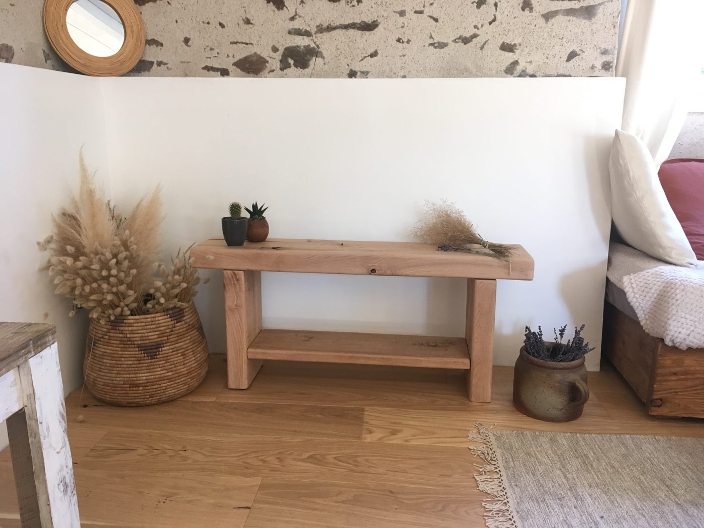 Banc long et fin en bois clair dans un salon aux murs de pierre