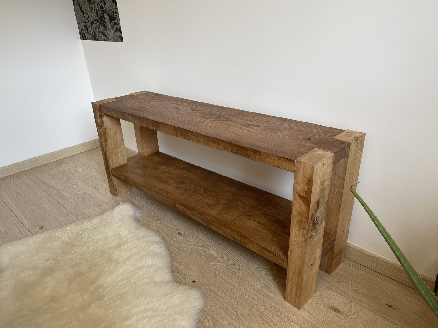 Banc console massif à étagère basse, posé contre un mur clair